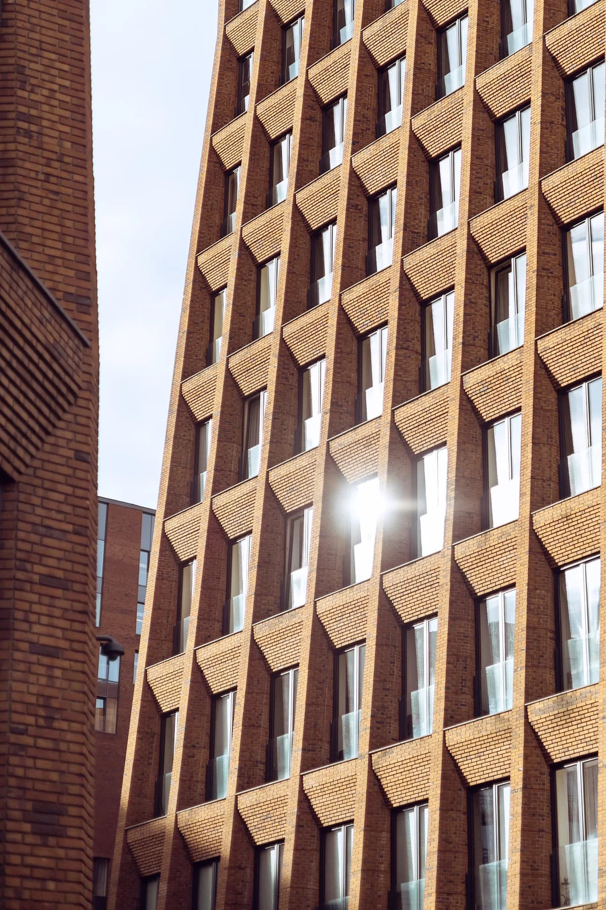 Gewerbefassade aus hellem Backstein, in einem Fenster spiegelt sich die Sonne