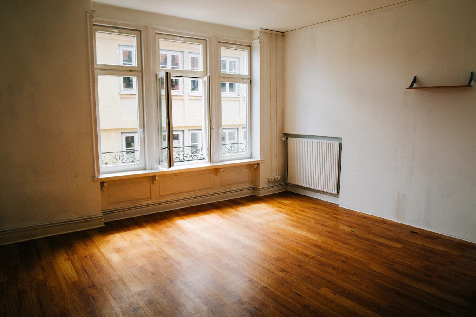 Leere Altbauwohnung mit Holzdielen, hohen Fenstern und Heizkörper unter der Fensterbank